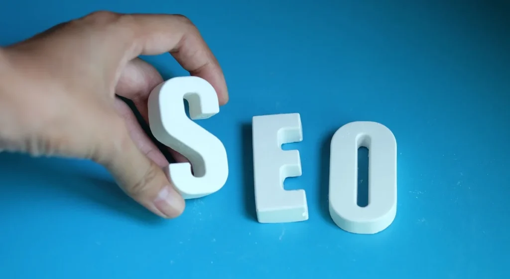 Hand placing the letter S in front of E and O to complete the word SEO, symbolizing search engine optimization